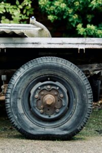 A close-up view of a worn commercial truck tire being inspected for tread depth and sidewall cracks.