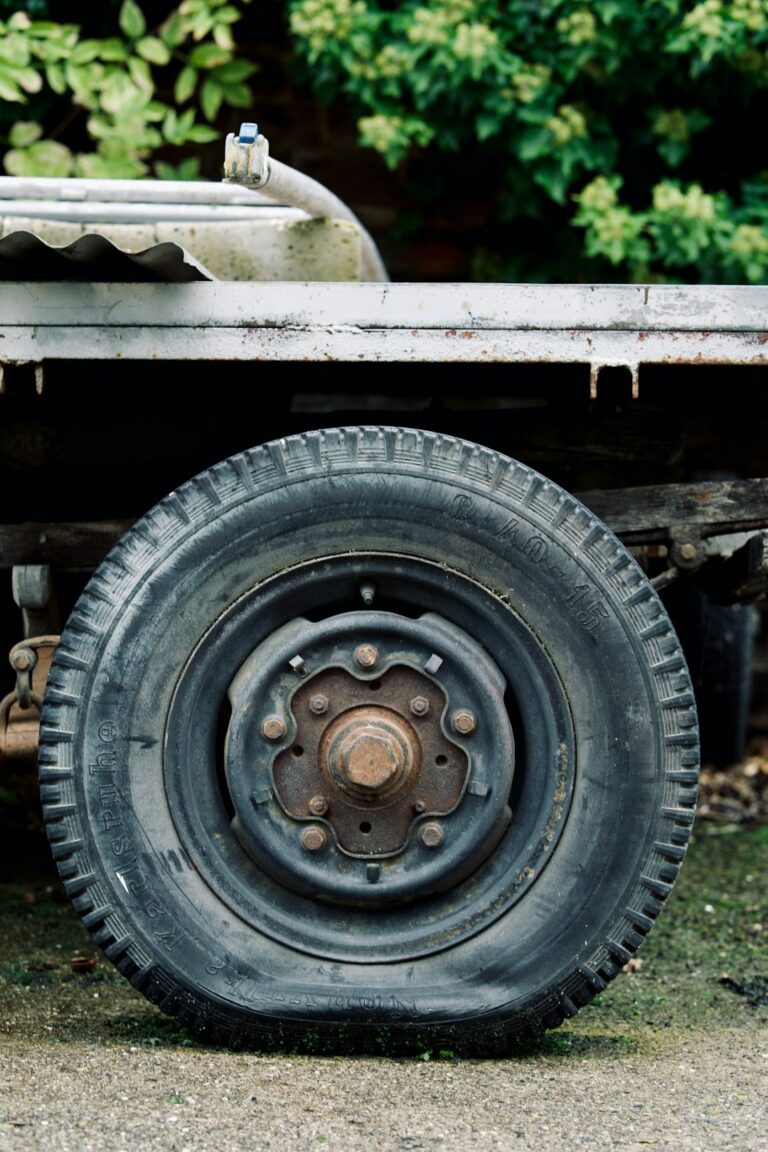 A close-up view of a worn commercial truck tire being inspected for tread depth and sidewall cracks.