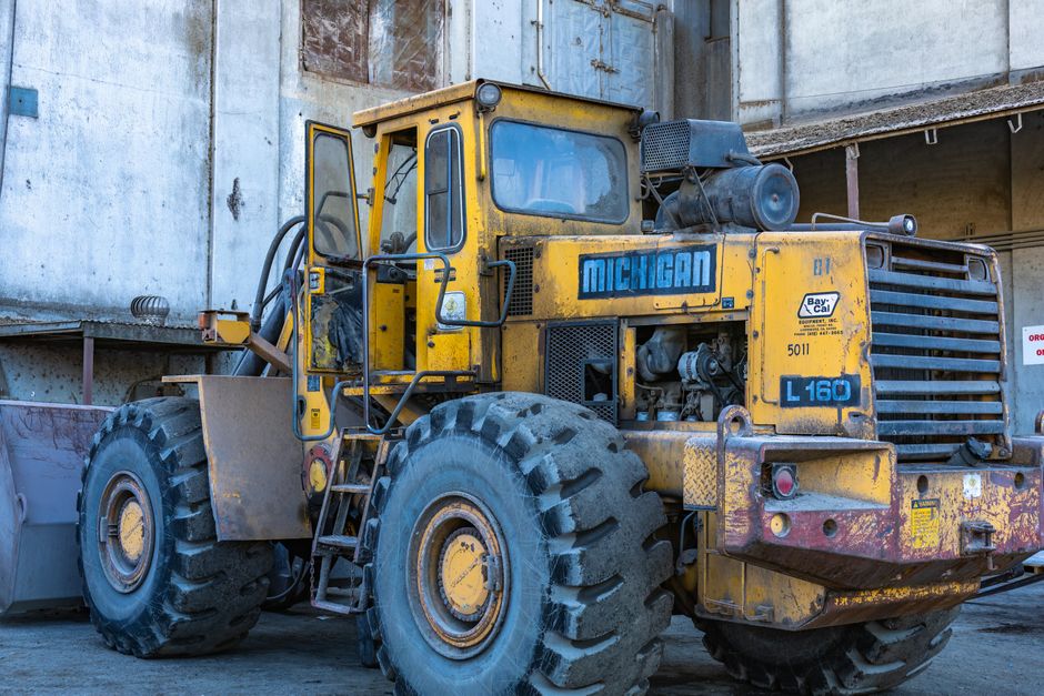 Commercial truck tires showing radial and bias ply construction beside a work vehicle on a paved lot